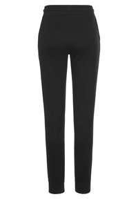 Schwarze Jogginghose mit schmalem Bein-Design, elastischem Bund und Bündchen an den Knöcheln. Hergestellt aus weichem, dehnbarem Stoff ohne sichtbare Hardware.