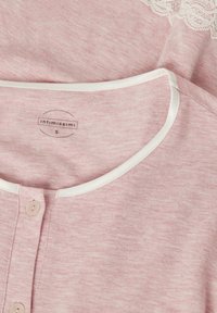 Ljust rosa topp med rundad halsringning och vit kant, knäppning framtill och spetsdetalj längs axeln.