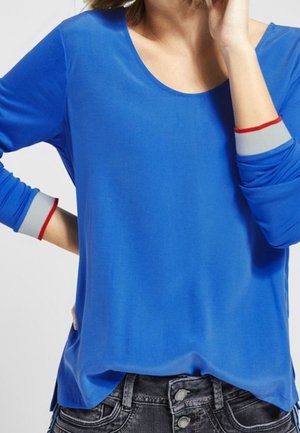 Top azul de manga larga con escote redondeado, con bandas de acento grises y rojas en los puños. Tejido suave con un ajuste relajado.