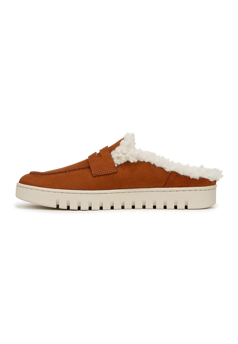 Chaussure slip-on en cuir brun avec une doublure blanche duveteuse, une semelle plate crème avec des bords nervurés et un simple détail de sangle.
