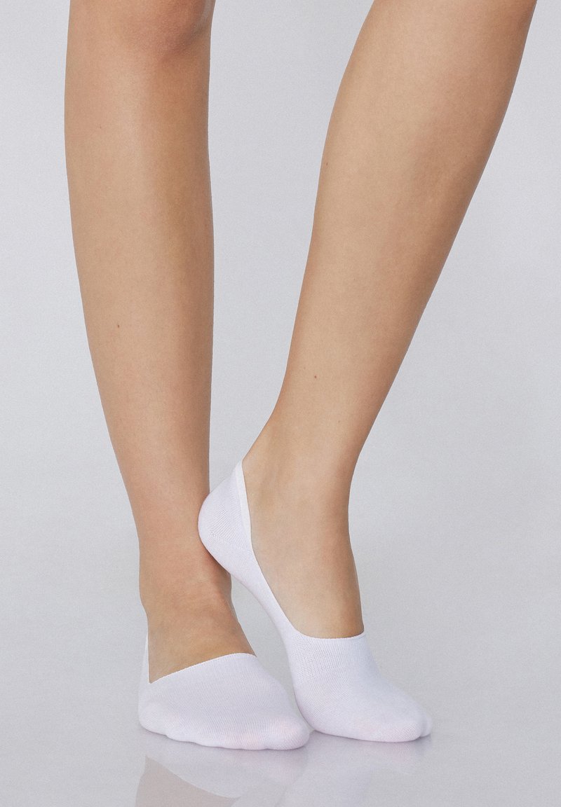 Weiße, unsichtbare Socken mit einem niedrigen Schnitt, aus weichem Material, das eine glatte Textur und eine enganliegende Passform um den Fuß bietet.