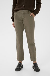 Pantaloni in misto cotone color khaki con gamba affusolata, tasche frontali e una vita con passanti per cintura, abbinati a mocassini neri.