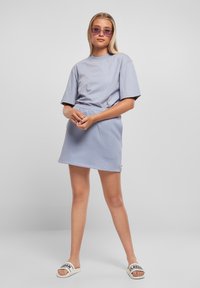 Světle modré bavlněné tričko a odpovídající mini sukně, obojí s volným fit. Model má na sobě fialové sluneční brýle a bílé skládací sandály.