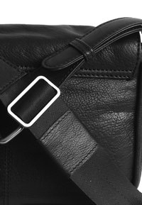 Borsa in pelle nera con superficie testurizzata, tracolla in nylon regolabile con fibbia rettangolare in argento e dettagli cuciti.