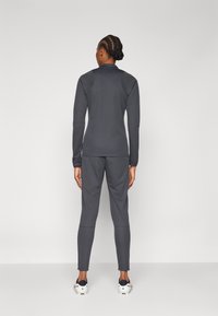 Grey athletic suit featuring a fitted long-sleeve top and tapered pants, made of stretchy fabric, with detailed seams and a smooth texture.