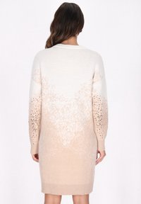 Beige pletené šaty ve stylu svetru s gradientním designem, zdobenými rukávy s kamínky a žebrovanými manžetami, které vytvářejí hladkou texturu.