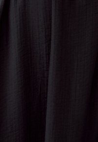 Black fabric with a textured surface, displaying subtle variations in weave and finish, drapes smoothly without visible patterns or accents.