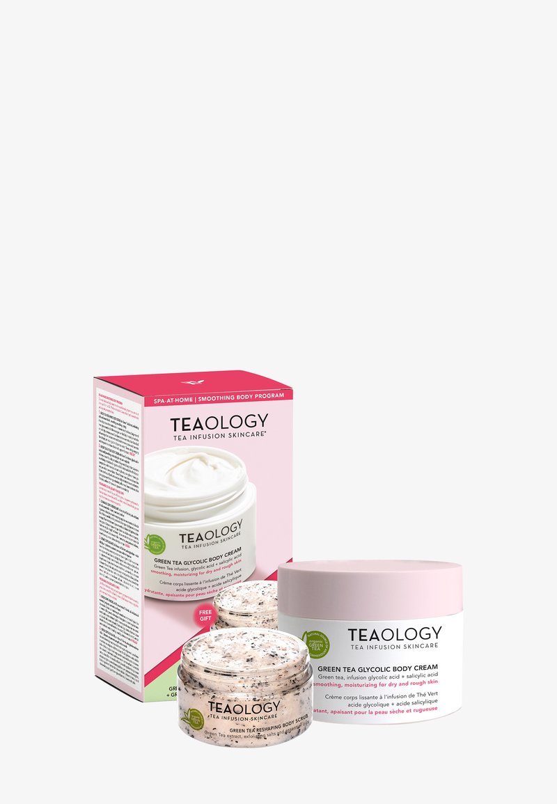 Zestaw pielęgnacyjny Teaology, zawierający glicolowy balsam do ciała z zieloną herbatą w białym słoiku z różową pokrywką oraz pasujący peeling do ciała.
