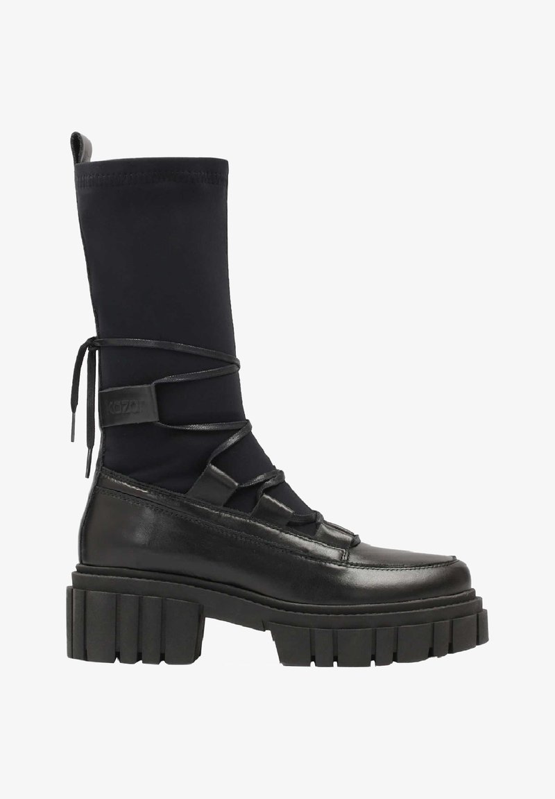 Bota negra hasta la rodilla que presenta una combinación de cuero suave y tejido elástico, con cordones en el frente y una suela gruesa y estriada.