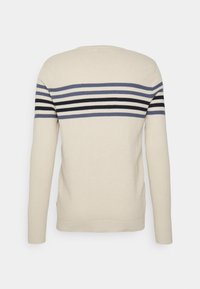 Beiger Pullover mit strukturierter Oberfläche, der auf dem Rücken und an den langen Ärmeln horizontale Streifen in Marineblau, Grau und Schwarz aufweist.