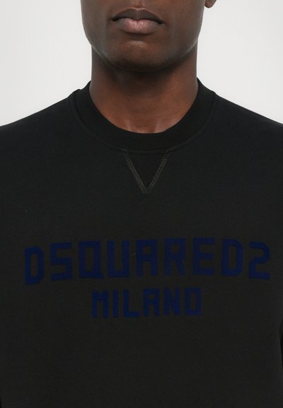 Sweatshirt noir avec un col rond et des coutures visibles. Présente une inscription en relief en lettres bleues "DSQUARED2 MILANO" sur la poitrine.