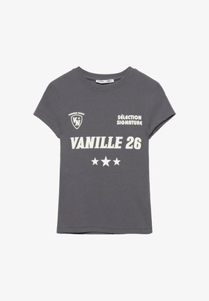Ciemnoszary t-shirt z krótkim rękawem z białym napisem „VANILLE 26”, trzema gwiazdkami, „SÉLECTION SIGNATURE” oraz logo w kształcie tarczy z napisami „VN” i „PERSIAN TOUCH”.