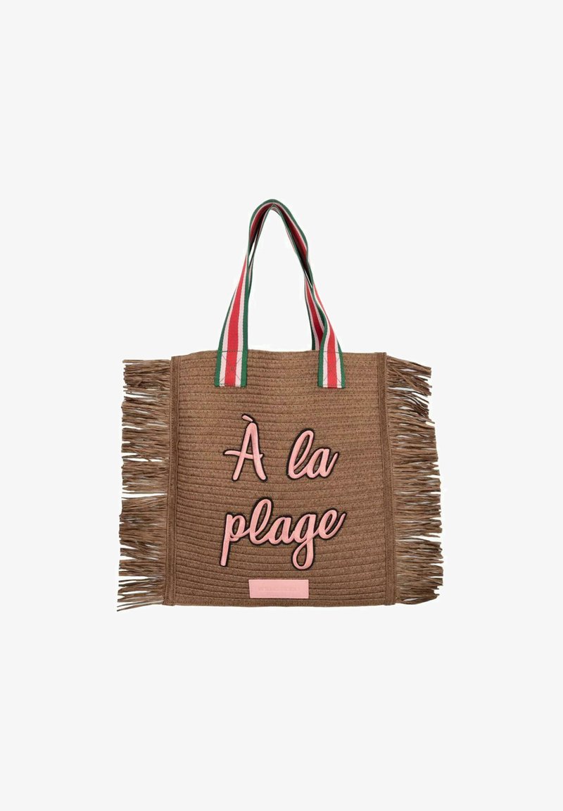 Bruine geweven tote bag met franjes, voorzien van roze "À la plage" tekst en gestreepte handvatten in rood, groen en wit.