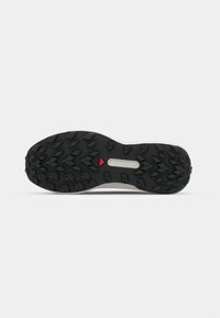 Semelle de chaussure de trail running, présentant une robuste semelle extérieure en caoutchouc noir avec des crampons multidirectionnels pour une meilleure adhérence, et une surface supérieure gris clair.