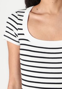 Svart og hvitstripet topp med rund hals og korte ermer, med ribbet tekstur og kontrastmønster.