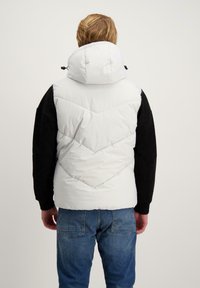 Witte puffer vest met een hoge kraag, chevron-stiksel en zwarte mouwen. Textuurstof, lichtgewicht ontwerp en casual pasvorm.