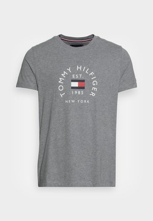 Szara koszulka z krótkim rękawem i okrągłym dekoltem z nadrukiem "Tommy Hilfiger", "EST. 1985", "New York" oraz logo flagi marki w kolorach czerwonym, białym i niebieskim na przodzie.