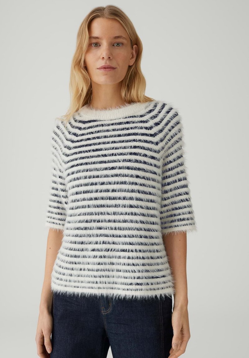 Weißer und marineblauer gestreifter Pullover mit kurzen Ärmeln, rundem Ausschnitt und weicher Textur, kombiniert mit dunklen Jeans.