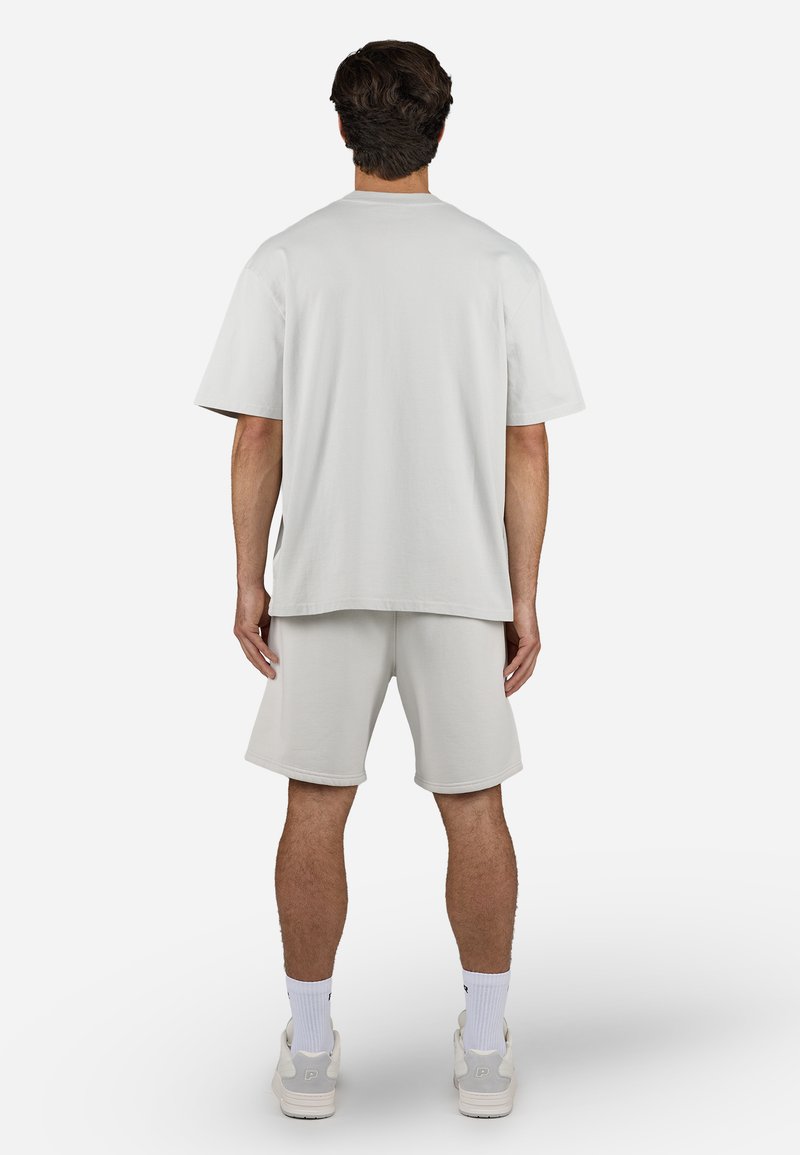 Hellgraues Baumwoll-T-Shirt und Shorts-Set, das eine lockere Passform und kurze Ärmel aufweist. Glatte Textur ohne sichtbare Muster oder Akzente.