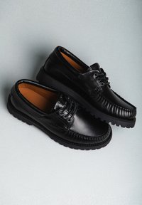 Scarpe in pelle nera con finitura liscia, punta arrotondata, cuciture a contrasto e suola in gomma spessa. Lacci e interno imbottito.