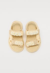 Sandales jaunes avec des accents floraux, dotées de deux sangles Velcro ajustables et de semelles en caoutchouc texturé pour une meilleure adhérence.