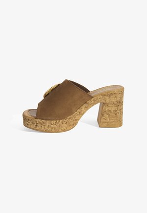 Braune Wildleder-Peeptoe-Sandalette mit hohem Absatz, korkbesetztem Blockabsatz und einem runden goldenen Akzent in der Mitte der oberen Öffnung.