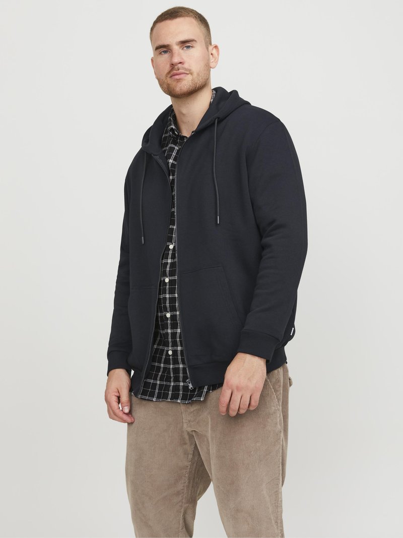 Mornarska hoodie s vezicama, prednjim rajsferšlusom i džepovima, složena preko crno-bijele karo košulje; smešane kord džinsice.