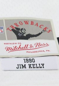 Mitchell & Ness Stoffetikett mit grauem Hintergrund, rotem Text "THROWBACKS" und schwarzem Text "1990 JIM KELLY", ergänzt durch eine schwarz-weiße Grafik.