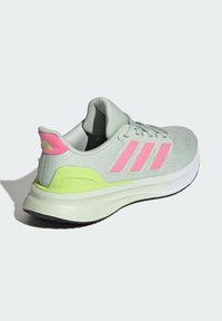 Zapatilla deportiva gris claro con detalles en rosa y verde, parte superior de tela texturizada y suela acolchada. Presenta tres rayas rosas en el lateral.