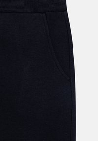 Marineblauwe joggingbroek met een geribbelde tailleband en zijzak, gemaakt van zacht textielmateriaal met een gladde textuur.