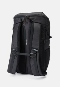 Mochila con un diseño aerodinámico, fabricada en tela negra con acolchado de malla en las correas, que cuenta con hebillas ajustables y un cierre de cremallera.