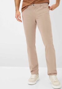 Lichtbeige katoenen broeken met een slim fit, voorzien van een sluiting met een voorste knoop en standaardzakken. Draagt samen met witte sneakers.
