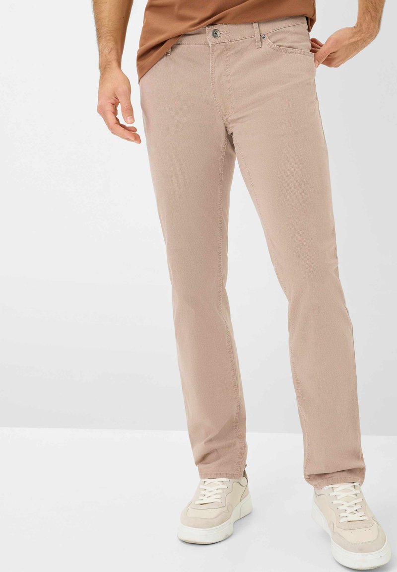 Lichtbeige katoenen broeken met een slim fit, voorzien van een sluiting met een voorste knoop en standaardzakken. Draagt samen met witte sneakers.
