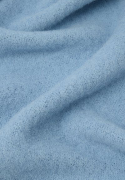 Soft light blue fabric with visible fibers and gentle folds creating subtle shadows and texture.