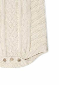Lys beige strikvarer med kabelstrikdesign og teksturerede sektioner; har fire trækknapper i træ nederst.