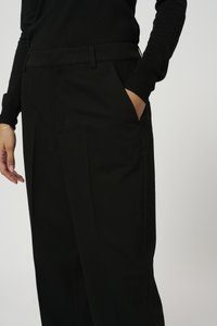 Zwarte broek met een rechte snit, voorzien van een platte voorkant, zijzakken en een gladde textuur. De tailleband is discreet en op maat gemaakt.