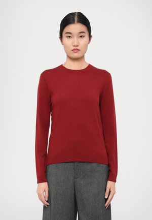 Maroon wool sweater with a round neck and long sleeves, featuring a ribbed hem and smooth texture, paired with gray wide-leg trousers.