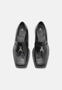 Zwarte lakleren loafers met een rechthoekige silhoutte, met een metalen insectaccent op de band en contrasterende stikdetails.