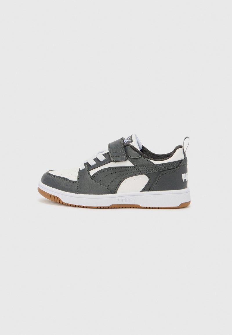 Chaussures de sport avec une tige en cuir gris et synthétique blanche. Dotées d'une sangle Velcro, de lacets blancs et d'une semelle en caoutchouc marron.