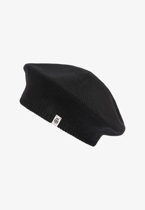 Black knitted beret with a small white tag featuring a black emblem, displayed against a white background.