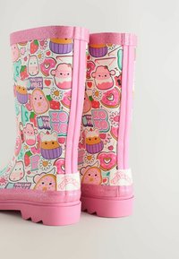 Färgglada regnstövlar med en glänsande vit botten och en lekfull design av sötsaker och karaktärer, rosa glittrande detaljer och en rosa sula.
