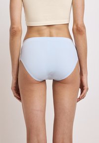 lichtblauwe katoenen damesonderbroek met een eenvoudig ontwerp, met een zachte textuur en een elastische tailleband, gezien vanuit de achterkant.