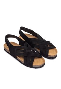 Sandales en suede noir avec design tissé, bout ouvert et style à bride arrière. Semelle en liège et semelle extérieure en caoutchouc texturé pour une adhérence optimale.