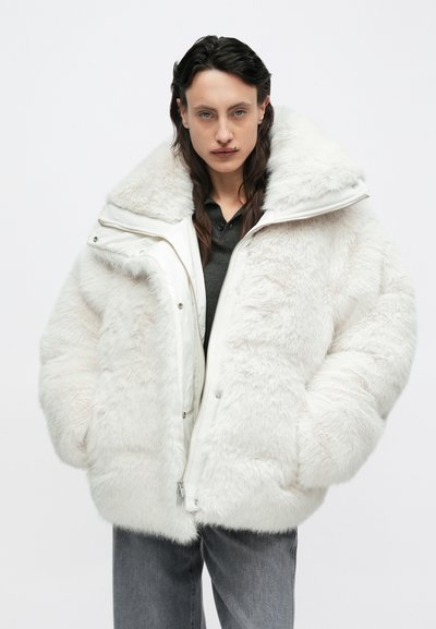 Fehér műszőrme túméretes dzseki magas gallérral, cipzáras záródással és nagy zsebekkel, puha, texturált felülettel és sima béléssel.