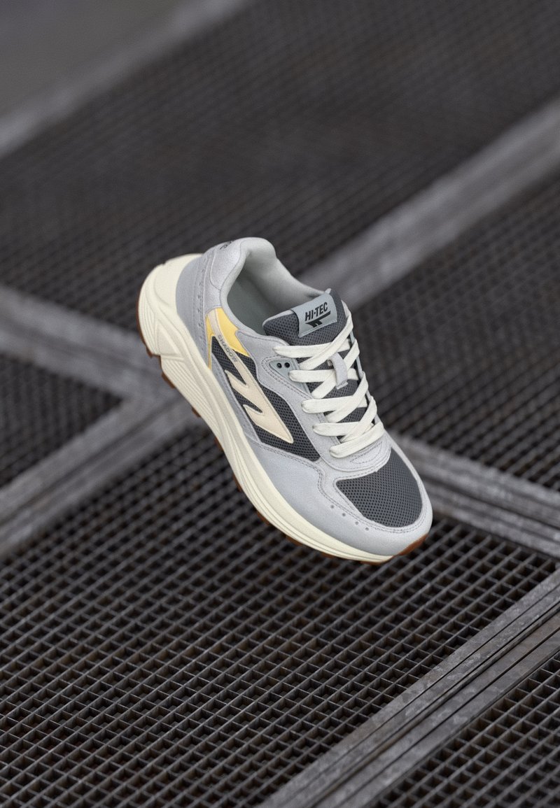 Gray and yellow athletic shoe featuring a mesh and suede upper, lace-up design, rubber sole, and textured accents.