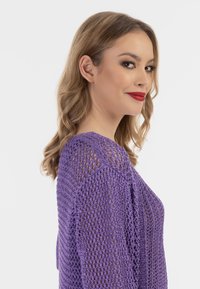 Pulover purpuriu, ușor, tricotat, cu o țesătură lejeră, guler rotund și mâneci lungi. Textură și design unice, cu accente de tricotare deschisă.