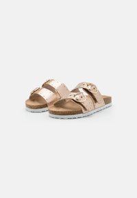 Roséguld sandaler med två justerbara remmar som har runda spännen och små nitar. Korkfotbädd och vit gummisula med texturerat grepp.