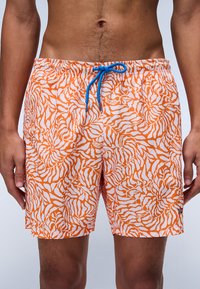 Patroon zwemshorts in oranje en wit met een golvend ontwerp, voorzien van een blauwe trekkoord en een elastische tailleband.