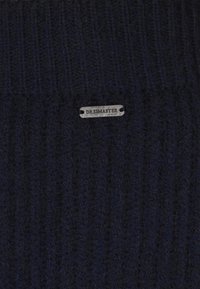 Căciulă din tricot ribbed de culoare bleumarin închis, având eticheta metalică argintie embosată cu numele brandului "DREIMASTER". Textură moale și design ajustat.