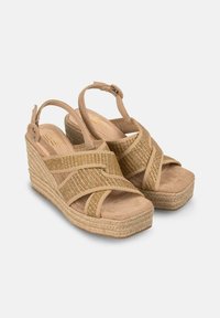 Sandales compensées beiges avec des brides croisées et des accents en tissage texturé, présentant une finition en nubuck doux et une semelle en jute tressé.